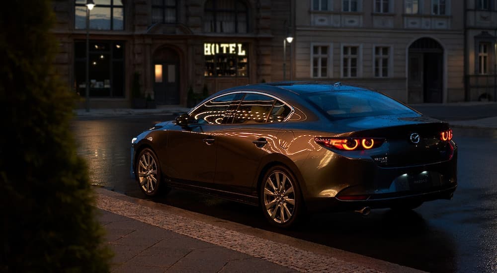 A grey 2025 Mazda 3 is shown from the rear at an angle after leaving an auto dealer near me.