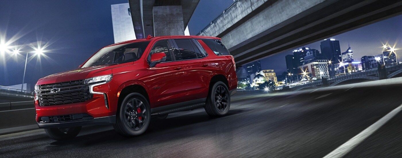 A red 2023 Chevy Tahoe is shown from the side after leaving a car dealer near Alpharetta.