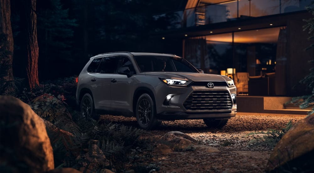 Grey 2026 Toyota Grand Highlander parked off-road near a building.