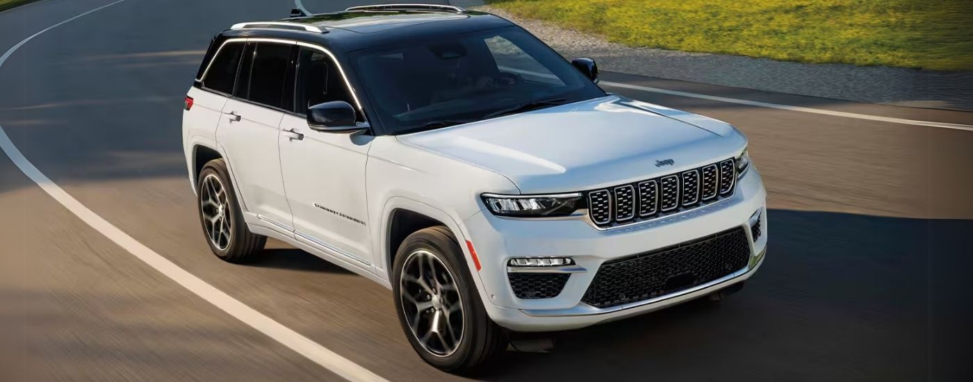 Cars%20for%20Sale%20Near%20Mount%20Pleasant%202025%20Jeep%20Grand%20Cherokee%20-%20White%20Driving.jpg White 2025 Jeep Grand Cherokee driving on a winding road