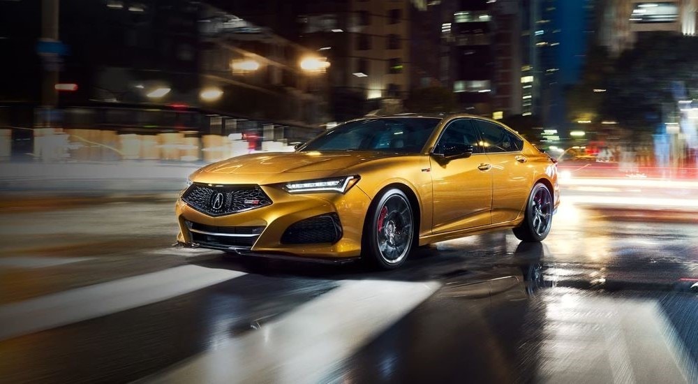 Car Dealership - 2022 Acura TLX Type S - Wet.jpg A yellow 2022 Acura TLX Type S is shown driving through a wet city intersection at night.
