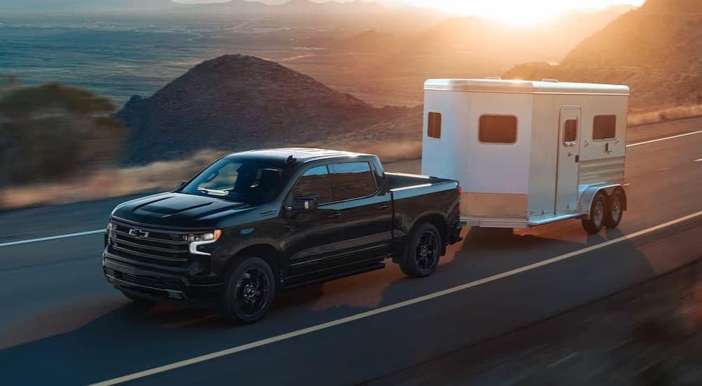 A black 2025 Chevy Silverado 1500 towing a trailer.
