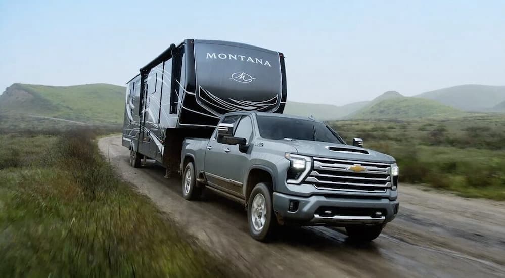 A gray 2025 Chevy Silverado 2500 High Country is shown towing a trailer.