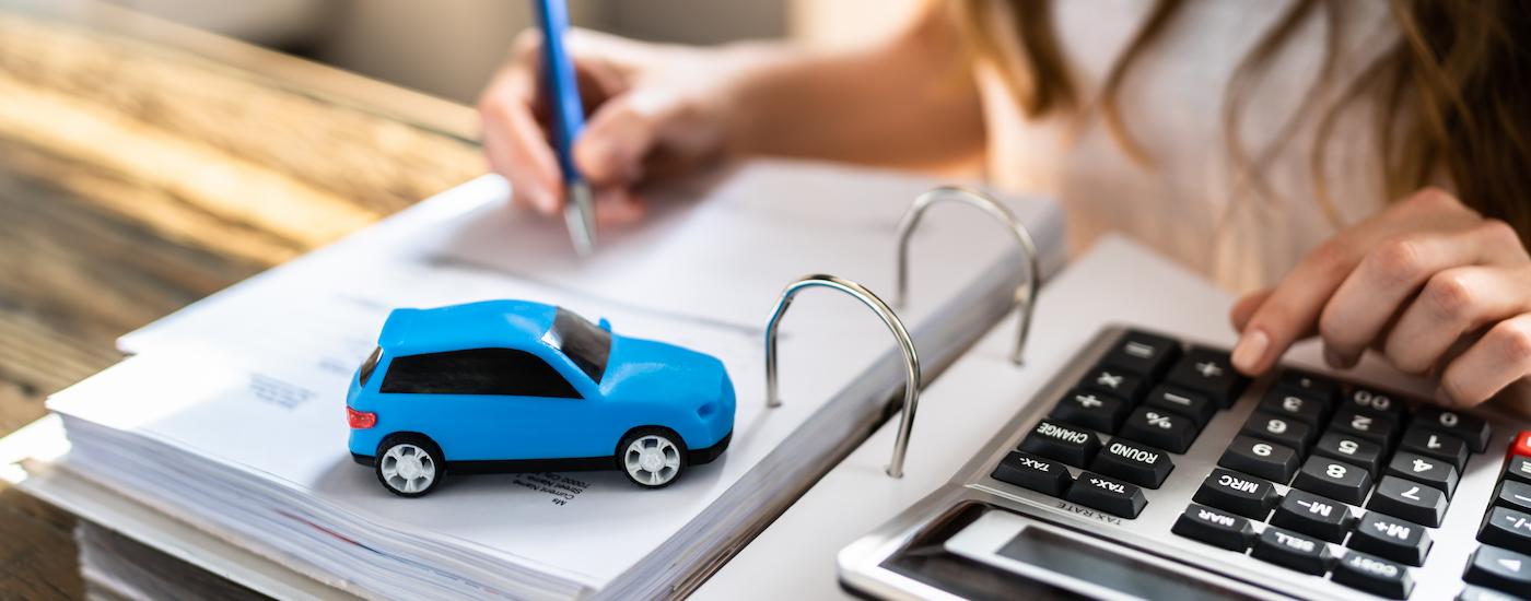 A blue toy car on vehicle financing paperwork.