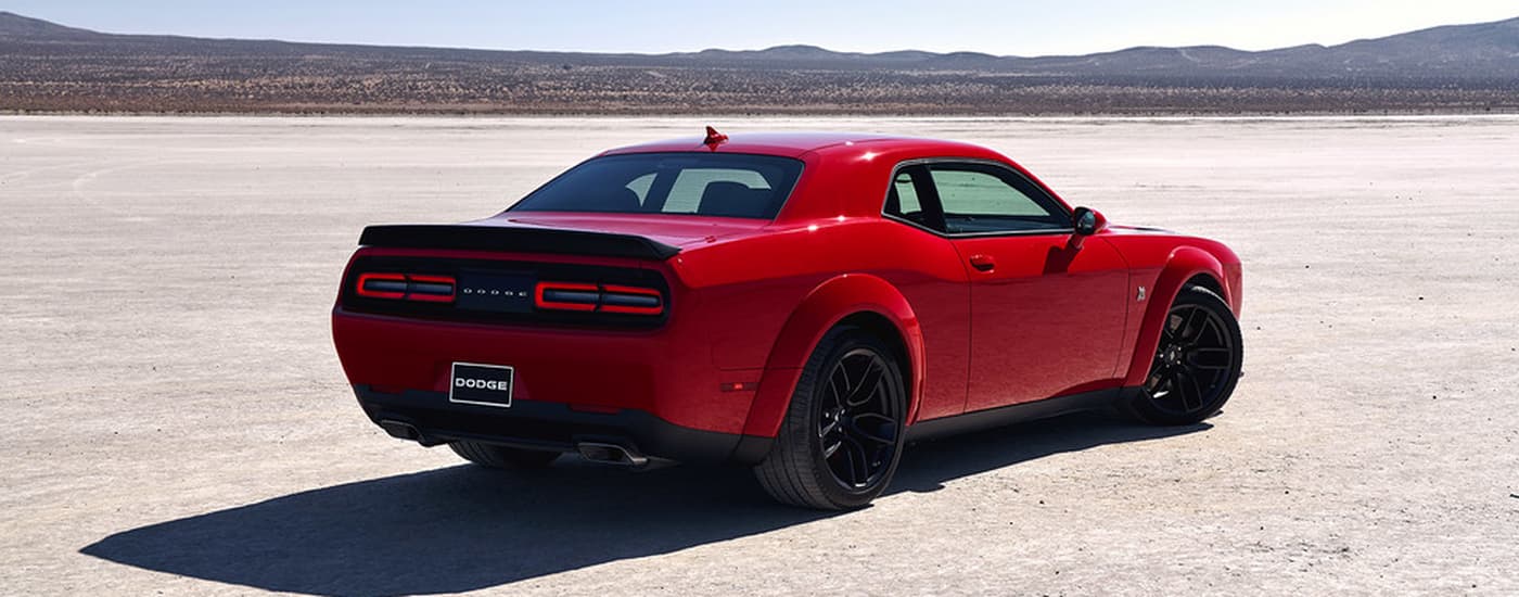 Red 2021 Dodge Challenger parked in an open dirt lot.
