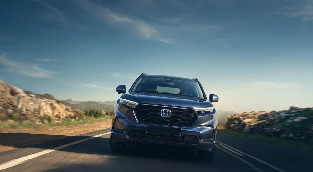 A blue 2025 Honda CR-V Hybrid is shown driving to a car dealer near Buford.