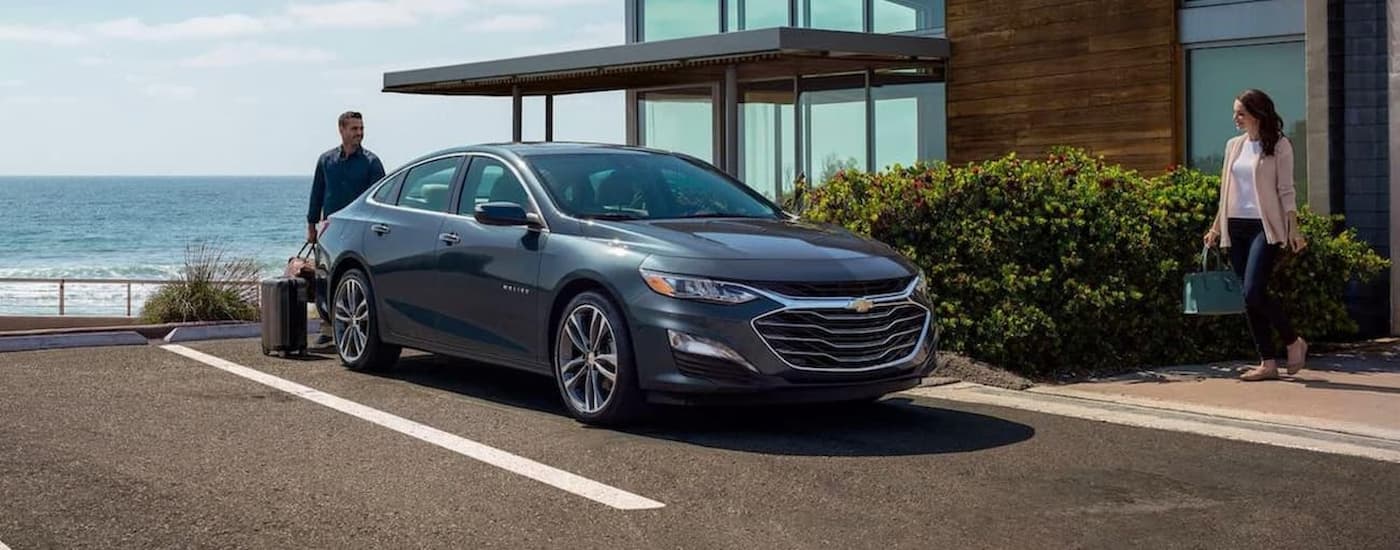 A grey 2020 Chevy Malibu is shown parked outside of a hotel.
