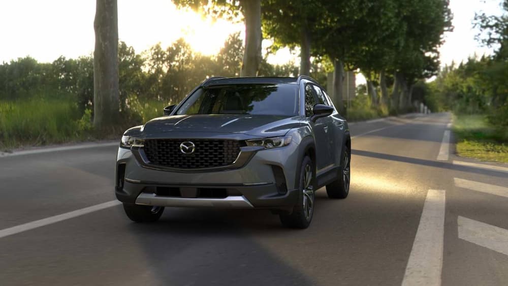 A gray 2025 Mazda CX-50 driving on a back road.