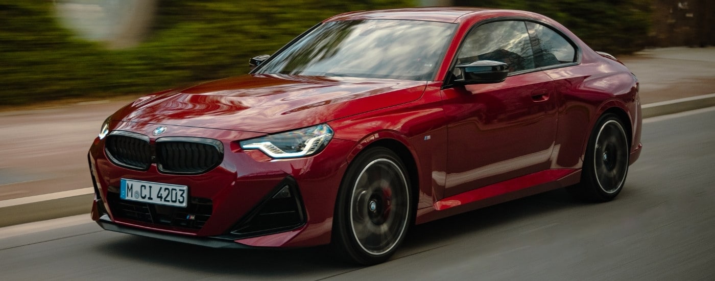 A red 2025 BMW M240i from the front at an angle after leaving a dealer that has cars for sale near Boiling Spring Lakes.