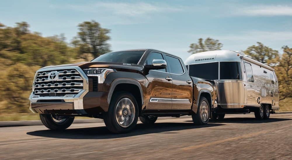 A brown 2025 Toyota Tundra towing a trailer after viewing trucks for sale.