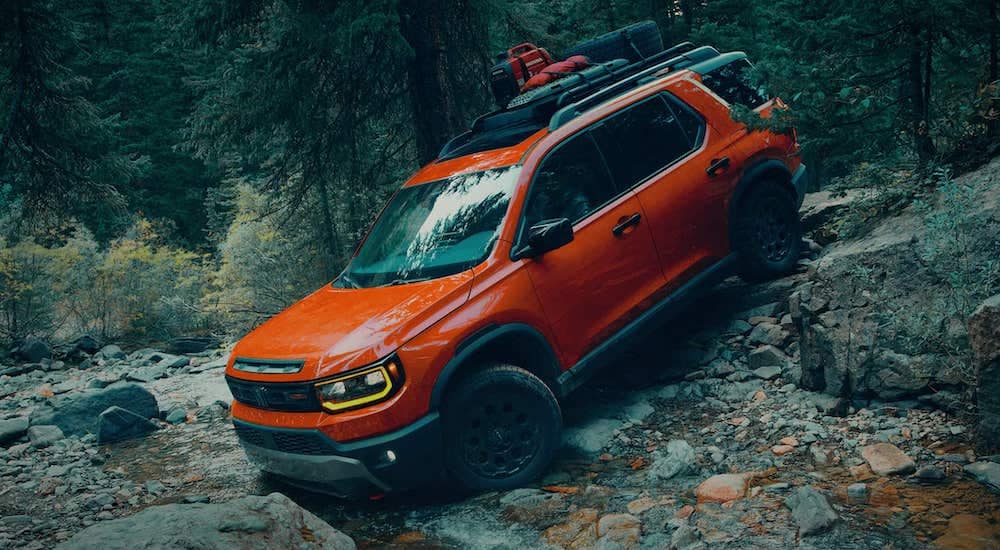 Orange 2026 Honda Passport driving down a hill.