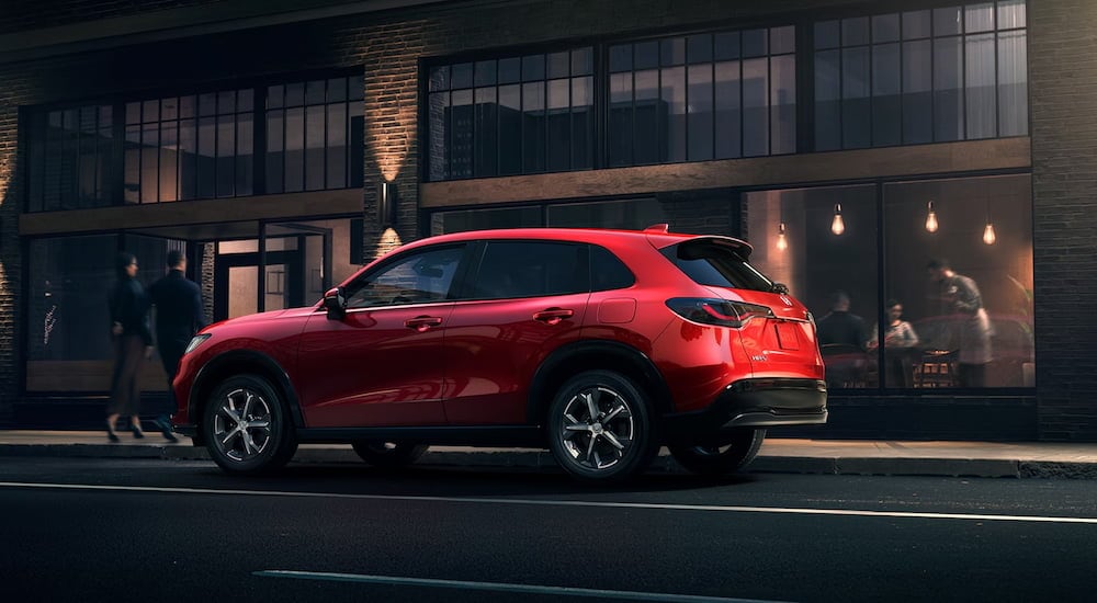 Rear view of a red 2025 Honda HR-V parked by a curb after visiting a dealer with Raleigh cars for sale.