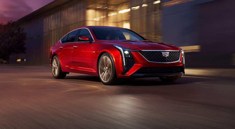 Red 2025 Cadillac CT5 driving by a building.