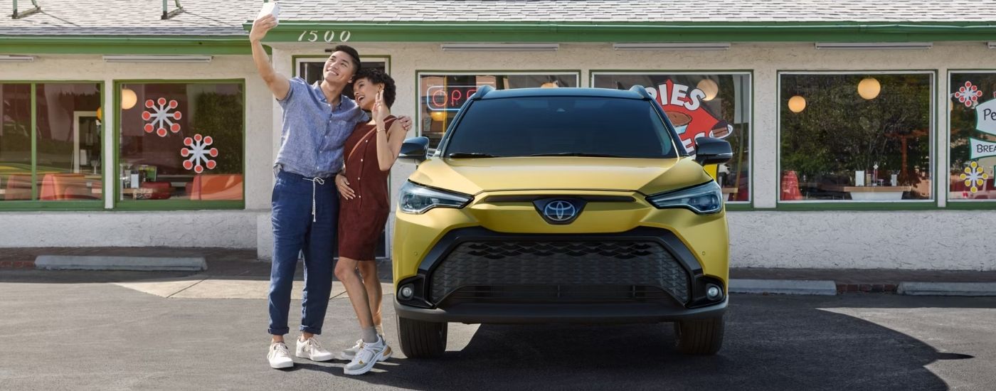 Yellow 2025 Toyota Corolla Cross parked in front of a store.