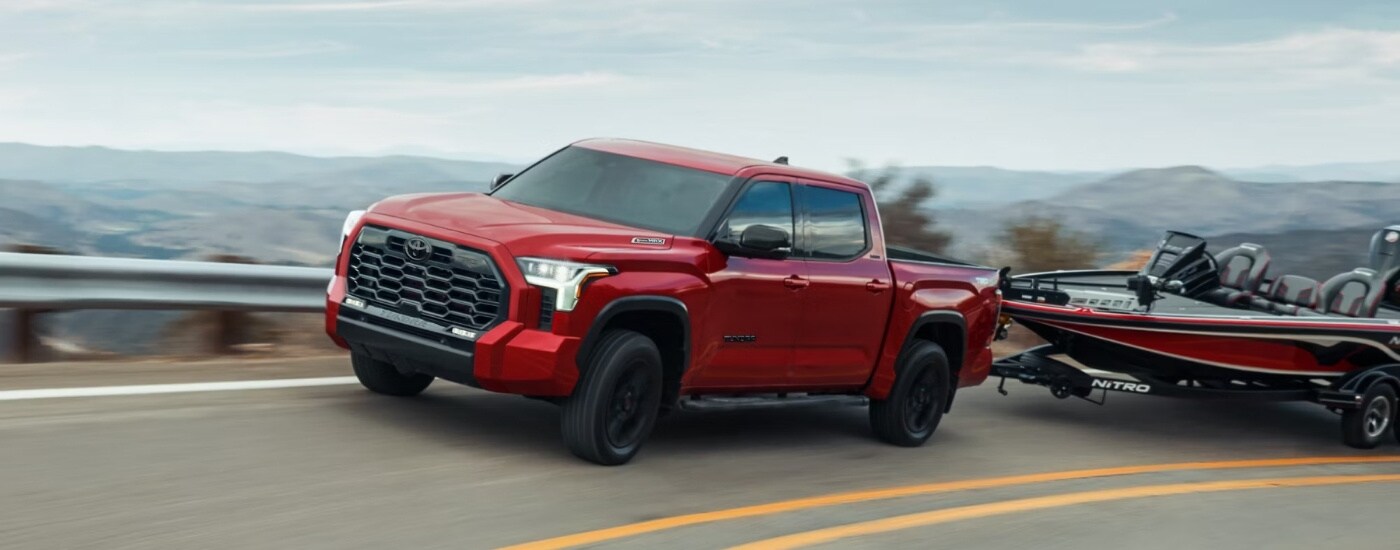 A red 2023 Toyota Tundra towing a boat.