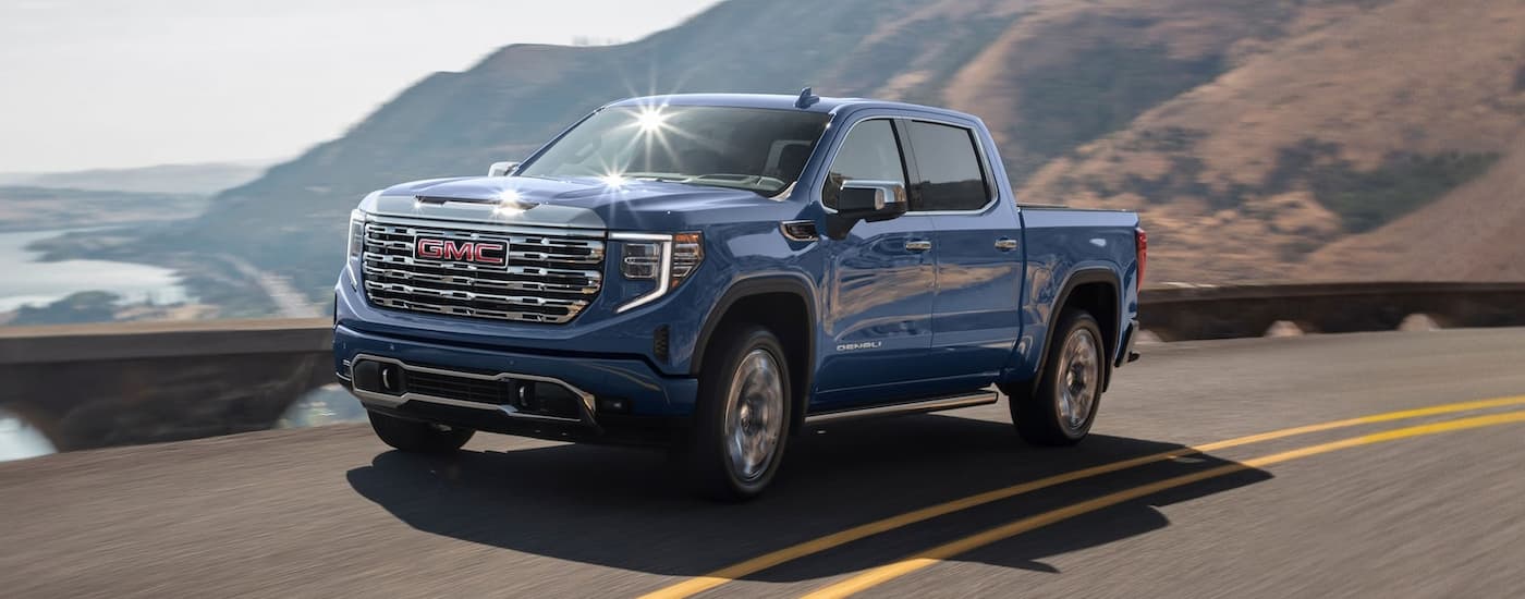 Trucks%20for%20Sale%20Near%20Concord%20-%202025%20GMC%20Sierra%201500%20Denali%20-%20Blue%20(1).jpg Blue 2025 GMC Sierra 1500 driving on a winding road