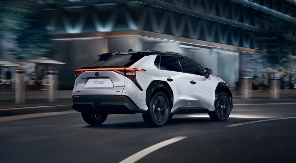 A white 2025 Toyota bZ4X Nightshade is shown driving to a car dealer near Duluth.